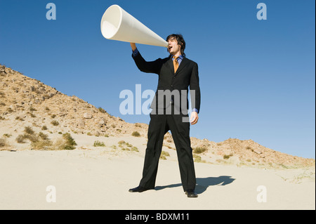 Geschäftsmann mit Megaphon in der Wüste Stockfoto
