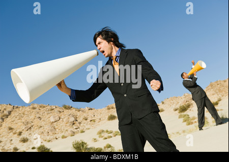 Zwei Geschäftsleute mit Megaphonen in Wüste Stockfoto