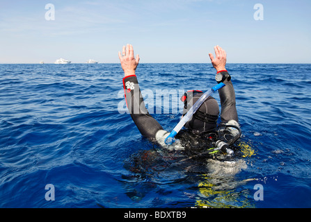 Taucher im Meer treibend versucht die Aufmerksamkeit der Menschen auf Tauchgang Schiffen am Horizont zu erhalten, durch winken, Ägypten, Rotes Meer, Afrika Stockfoto