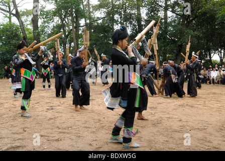 Männer und Frauen eines Lusheng-Orchesters in traditionellen Kostümen der Basha Minderheit von ausgetretenen schwarzer Baumwolle mit Bambusflöten Stockfoto