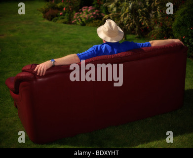 Mann sitzt auf einem Sofa im Garten. Stockfoto