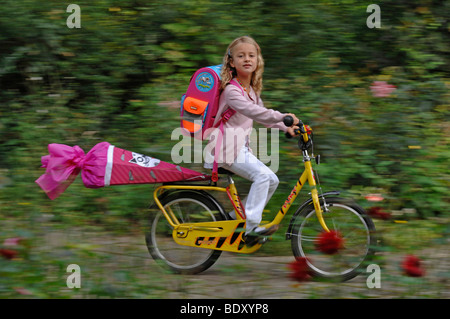 Sechs-jährigen Mädchen mit erste-Tag-der-Schule-Cornet auf ihrem Fahrrad Stockfoto