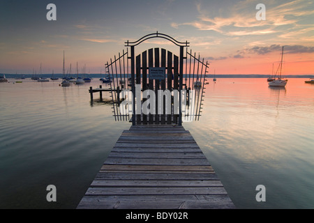 Ein geschlossenes Tor am Ende eines Piers vor einer bunten Abendhimmel am Ammersee-See in der Nähe von Herrsching, Bayern, Deutschland, Europa Stockfoto