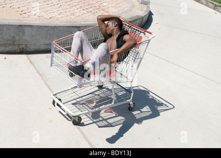 Afro-Amerikaner ist in einem Warenkorb nach einer exzessiven Party ohnmächtig. Stockfoto