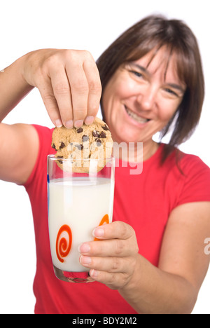 Eine Frau glücklich tunkt ihr mit Schokosplittern in ein kaltes Glas Milch. Stockfoto