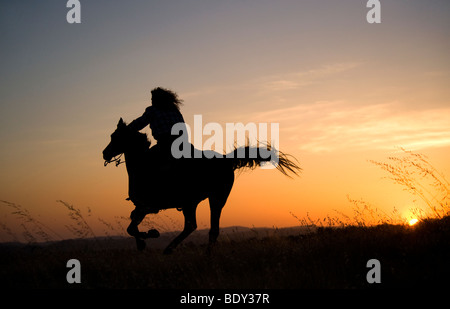 Frau reitet ihr Pferd bei Sonnenuntergang Stockfoto
