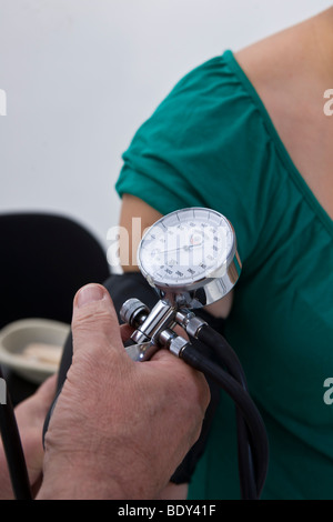 Arzt den Blutdruck eines jungen Patienten messen Stockfoto