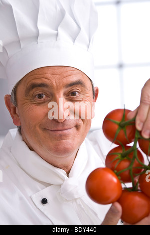 Koch ein Koch Hut strauchtomaten in seiner Hand hält Stockfoto