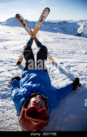 Kind auf Skiern im Schnee liegen. Stockfoto