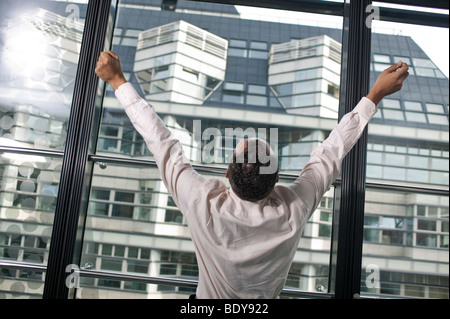 Mann am Fenster, mit erhobenen Armen Stockfoto