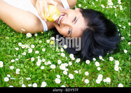 Frau, Essen einen Apfel in die Gänseblümchen Stockfoto