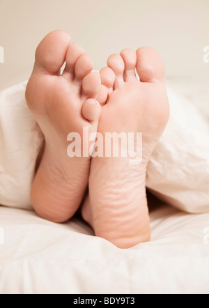 Zwei Füße ragte aus weißen Bettdecke Stockfoto
