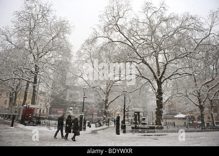 Drei Menschen zu Fuß vorbei an Leicester Square, London, im Schnee. Stockfoto