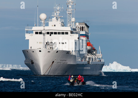 Eco - Touristen im Schlauchboot Zodiac Boot zurück zu verankert Expedition Kreuzfahrtschiff in der Antarktis, blauer Himmel, blaues Wasser, große Eisberge im Hintergrund Stockfoto