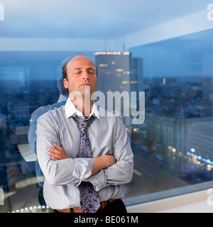 Business-Mann lehnte sich gegen das Fenster Stockfoto