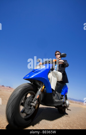 Ein Mann in einem Anzug reitet einen Motorroller auf einer Landstraße in Santa Barbara, Kalifornien Stockfoto