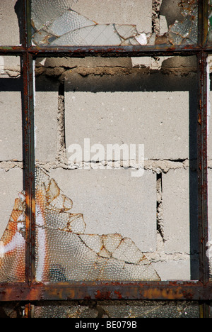 Außenseite des zerbrochenen Fenster zugemacht von innen mit Betonsteinen bilden einen bunten städtischen Gittermuster Stockfoto