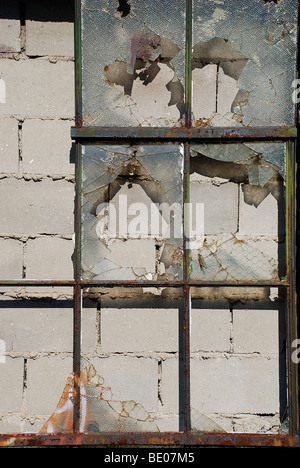 Außenseite des zerbrochenen Fenster zugemacht von innen mit Betonsteinen bilden einen bunten städtischen Gittermuster Stockfoto