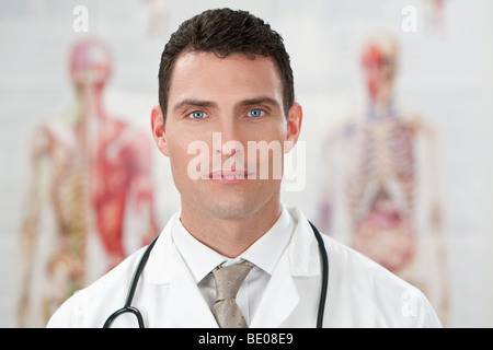 Einen männlichen Arzt in einem weißen Kittel mit Stethoskop stand vor menschlichen Anatomie Diagramme. Stockfoto