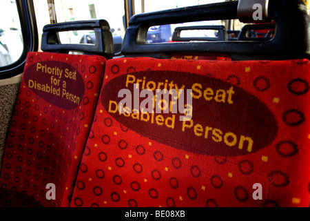 Leuchtend rote Priorität Sitzplätze für behinderte Menschen in einem Bus in Brighton, East Sussex, UK. Stockfoto