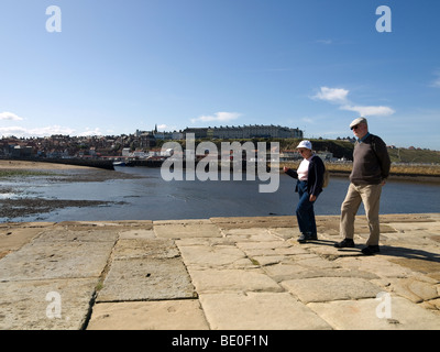 Genießen Sie die Sonne ein Ehepaar im Ruhestand schlendern Sie gemeinsam am East Pier Whitby North Yorkshire Stockfoto