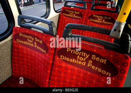 Leuchtend rote Priorität Sitzplätze für behinderte Menschen in einem Bus in Brighton, East Sussex, UK. Stockfoto