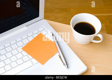 Leere orange Postit Hinweis auf weißen Laptop-Tastatur mit Stift und Tasse Kaffee Stockfoto