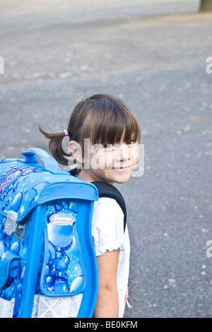 Junges Mädchen mit einem Ranzen, auf dem Schulhof Stockfoto