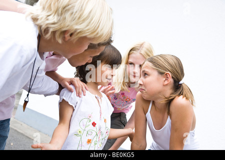 Junge Schülerin auf dem Schulhof, im Gespräch mit älteren Kindern Stockfoto