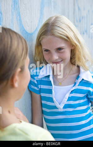 Zwei Mädchen, die an eine Wand gelehnt reden Stockfoto