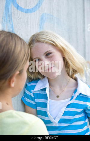 Zwei Mädchen, die an eine Wand gelehnt reden Stockfoto