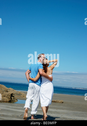 Paar, gehen Arm in Arm auf dem Strand und Blick auf das Meer Stockfoto