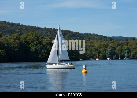 Yacht vorbei Tempolimit Boje (6mph) auf See Windemere, Nationalpark Lake District, Cumbria, England UK Stockfoto