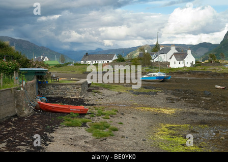 Bei Ebbe entlang der Ufer von Plockton Harbourt mit weißen Häuschen im Hintergrund und die Wester Ross Berge. Stockfoto