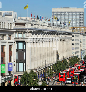 Die Oxford Street Front von Kaufhaus Selfridges mit Fahnen auf dem Dach Level & roten Londoner Busse West End London England UK Flying Stockfoto