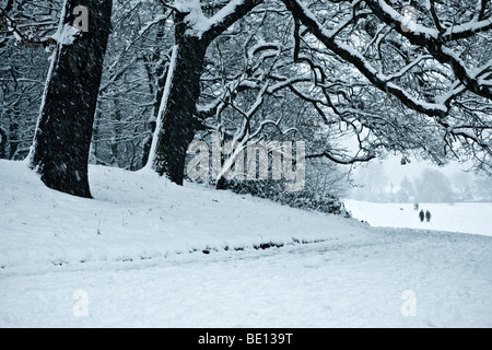 Menschen zu Fuß nach Hause durch eine verschneite Landschaft, die durch Bäume gerahmt Stockfoto