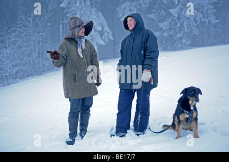 zwei Frauen, die ihren Hund im Schnee Stockfoto