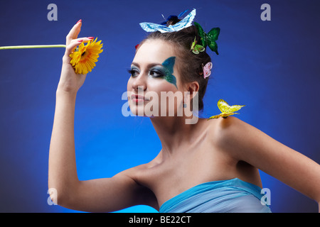 Porträt von schönen Modell mit Bodyart und-RNA Schmetterlinge Schmetterling auf ihrem Finger und Haare, mit Blume in der hand Stockfoto