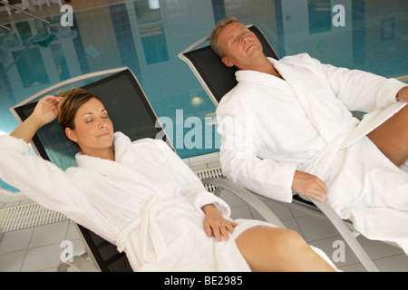 paar liegt auf einem Liegestuhl neben einem Spa-pool Stockfoto