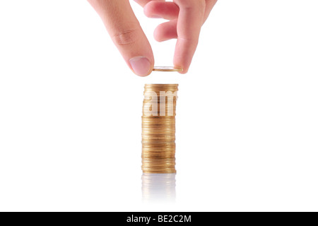 Hand eine Münze zu einem Stapel von Münzen hinzufügen Stockfoto
