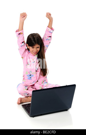 Junges Mädchen gekleidet im Pyjama mit Laptop und Arme angehoben - isoliert auf einem weißen Hintergrund Stockfoto