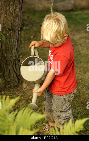 Ein drei Jahre alter Junge spielt mit einem Outdoor-Vintage Hand Wasser Pumpe Garten Stockfoto