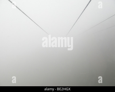 Seilbahn-Kabel in dicke Wolke oder Nebel verschwindet Stockfoto