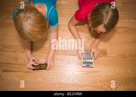 zwei Kinder Berechnung zahlen, eins mit einem Abakus angetrieben mit einem solar Taschenrechner Stockfoto