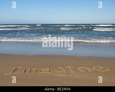 IMAGINE geschrieben auf dem Sand am Meer. Stockfoto