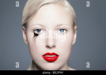 Porträt einer jungen blonden Frau mit verschmierten Eyeliner mit Blick auf den Betrachter, unvollkommen, Schönheit Stockfoto