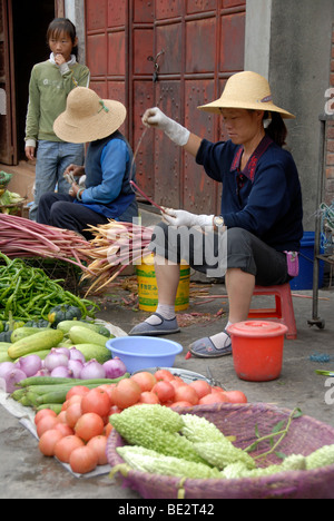 Marktfrauen mit Hut sitzt auf einem Markt Abwürgen, frisches Gemüse, Dali, Yunnan Provinz, Volksrepublik China, Asien Stockfoto