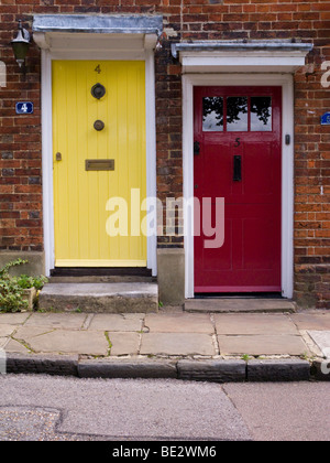 Zwei bemalte Eingangstüren in gelb und rot, in Folge des viktorianischen Reihenhäuser / Hütten. Farnham, Surrey. VEREINIGTES KÖNIGREICH. Stockfoto