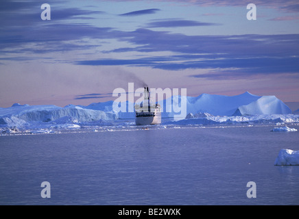 Kreuzfahrtschiff vor Eisbergen, einem Ice Fjord, UNESCO-Weltkulturerbe, Ilulissat, Grönland Stockfoto