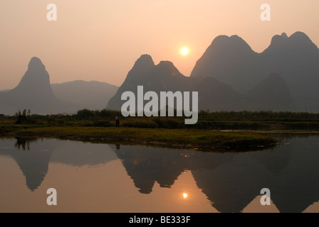 Karst-Klippen und Reisfelder in der Abendsonne zur Erntezeit im Yulong River in die steinige Karstlandschaft spiegeln Stockfoto